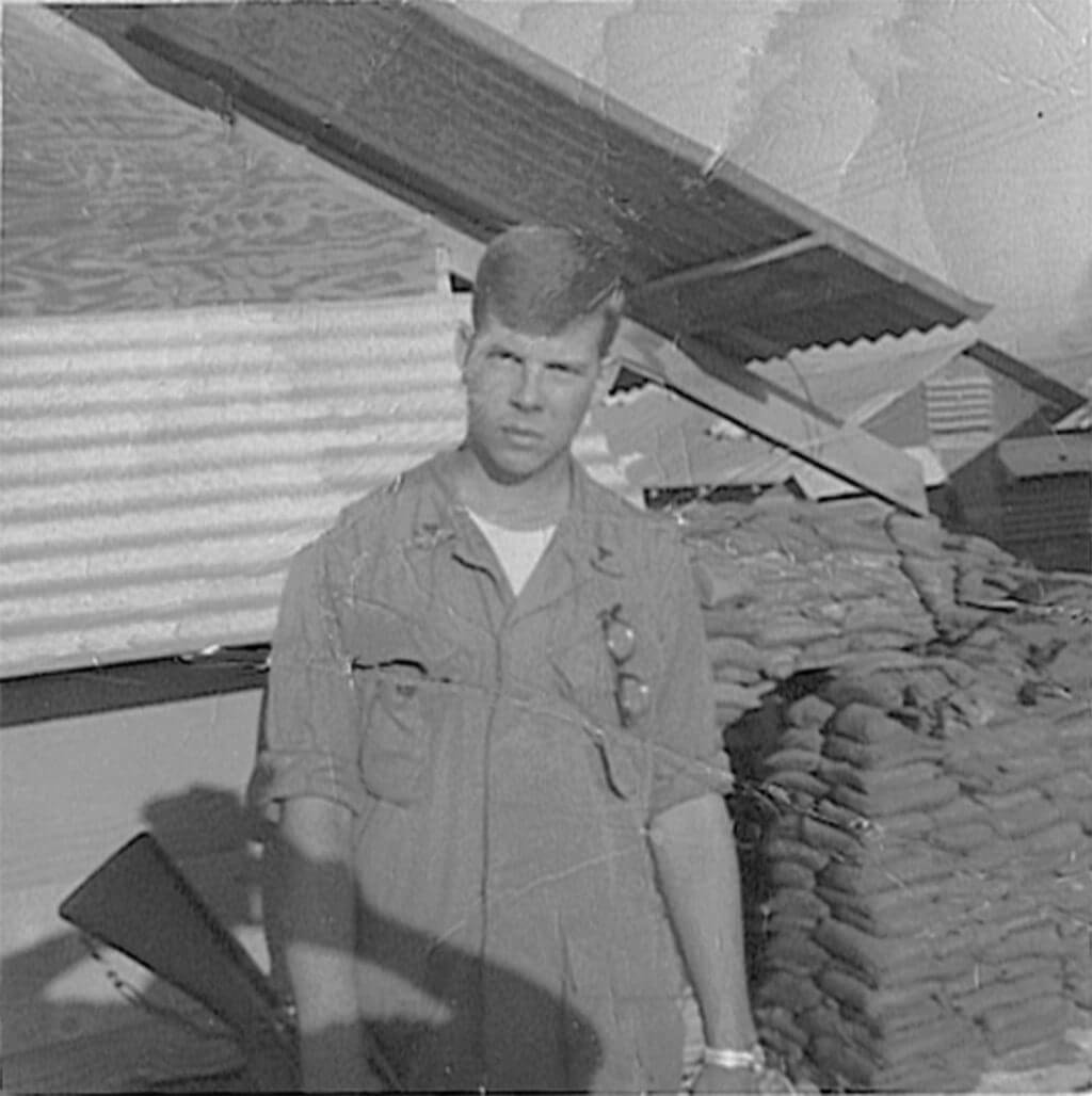 Stern-looking young soldier standing outside barracks.