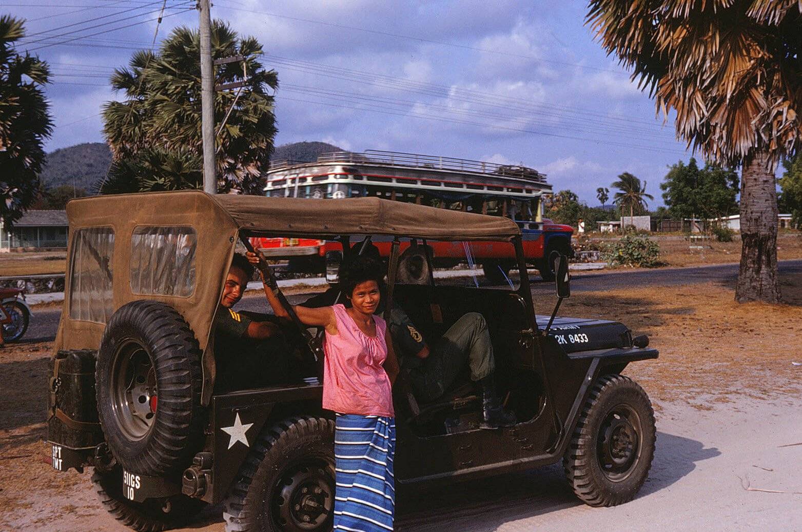 An Asian woman standing near a Jeep.