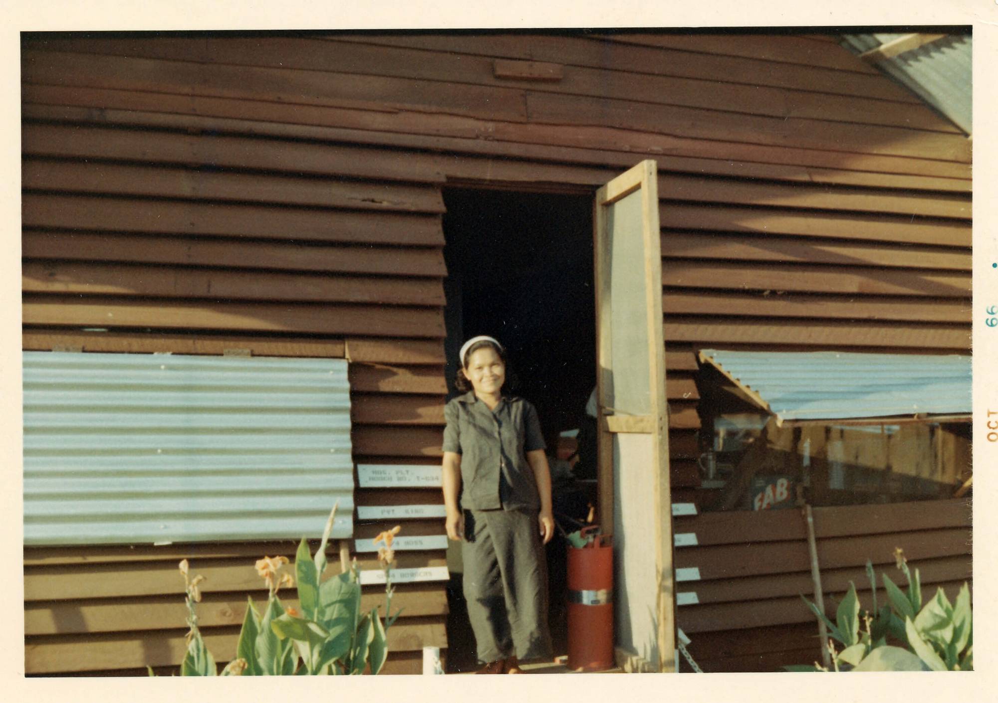 A young Asian woman standing in a doorway. Photo margin indicates the photo is from October 1966.