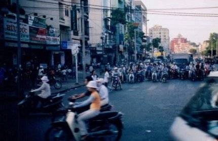 A city street with lots of Vietnamese people on motorbikes.