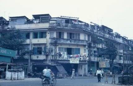 A city street with a building, laundry hanging on a line outside.