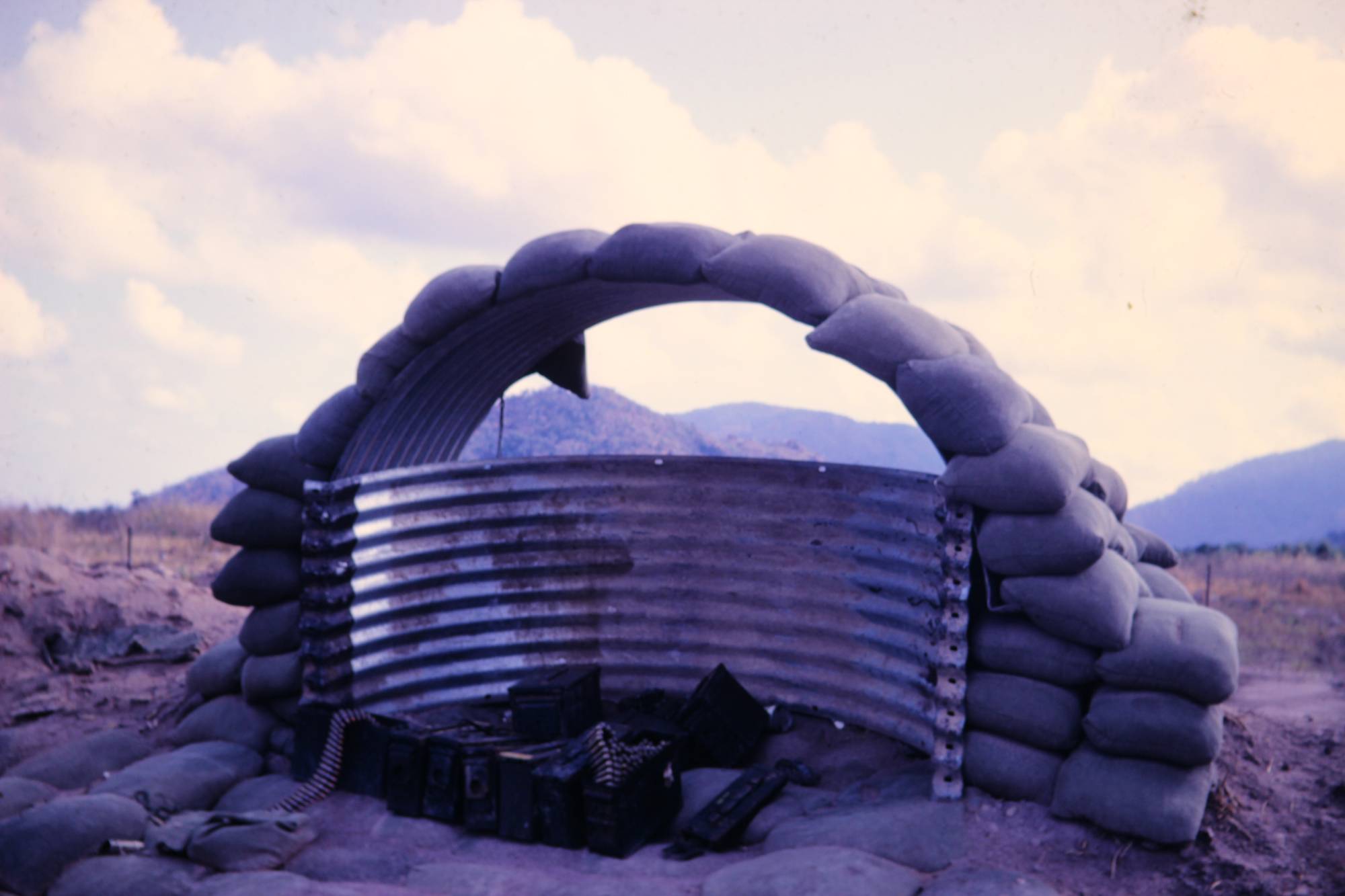 A guard station on top of a hill, made from corrugated metal and sandbags.