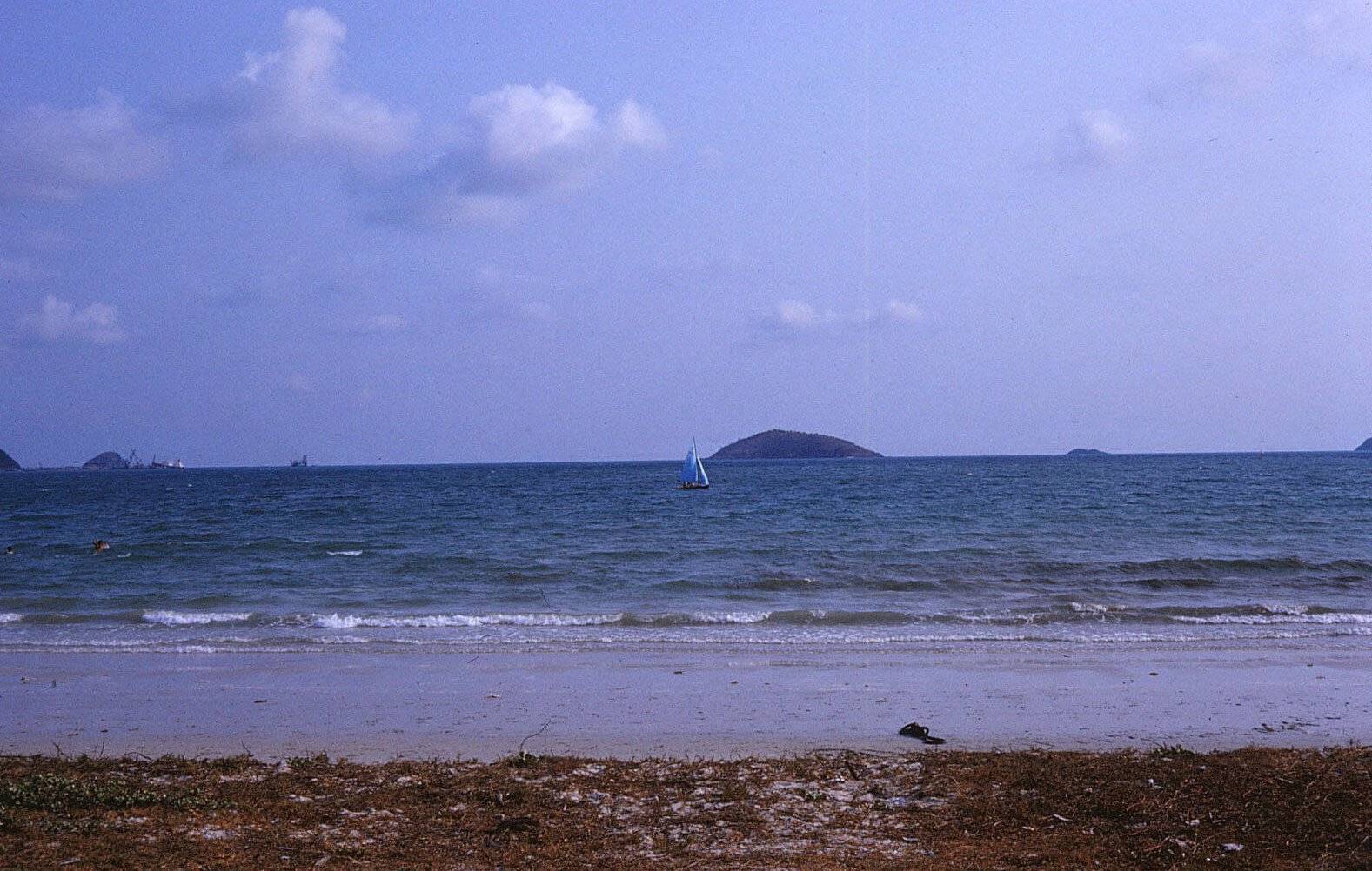 An ocean with a small sail boat on it.