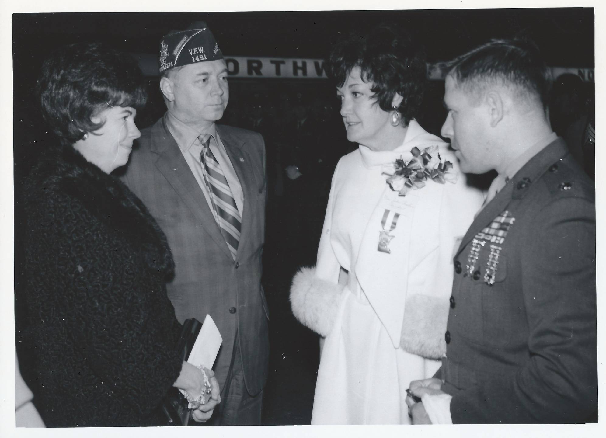 Two servicemen and two women conversing.