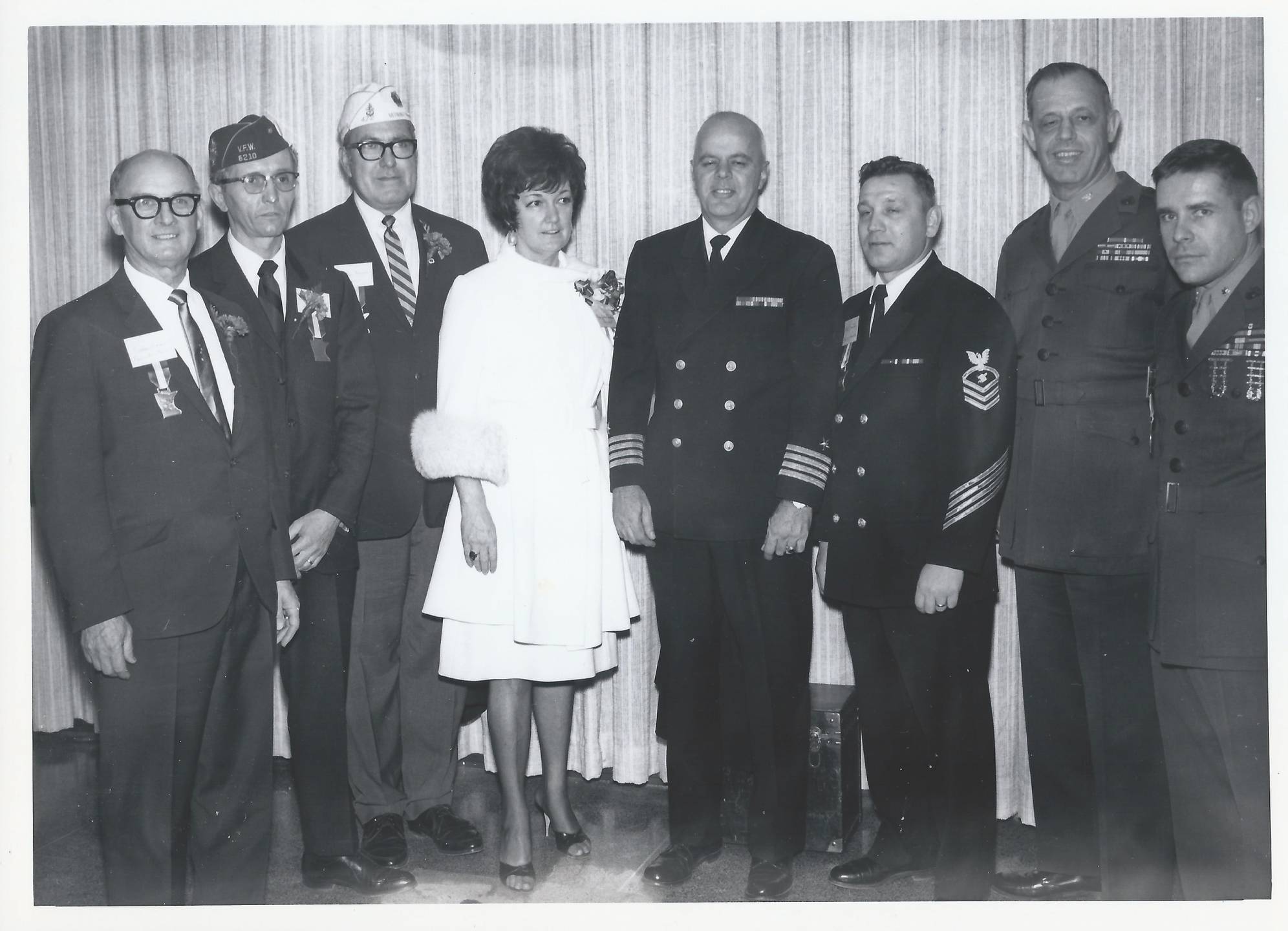 Posed photo of several servicemen, one civilian man, and one civilian woman.