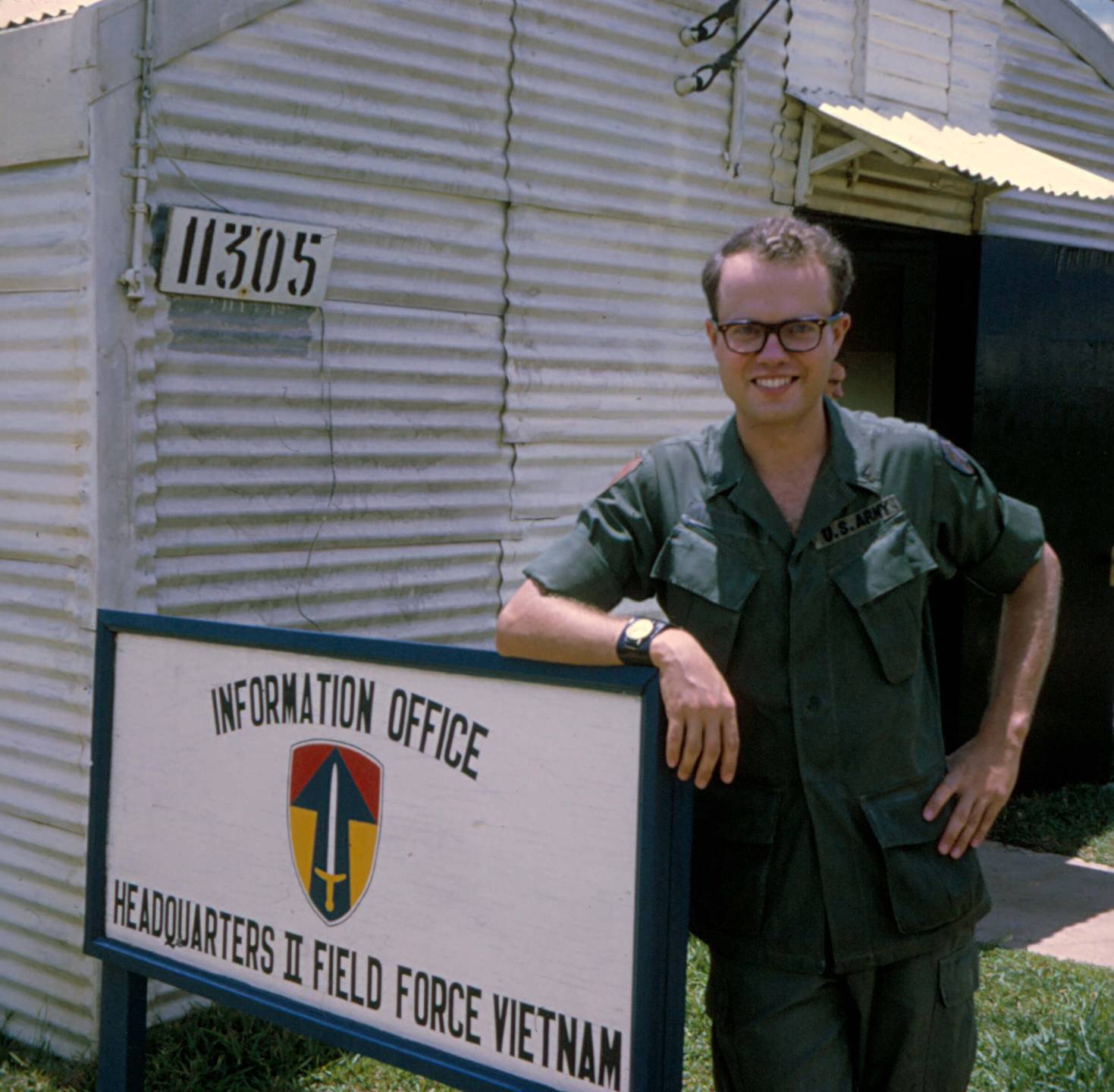 Young U.S. soldier leaning against an Information Office sign.