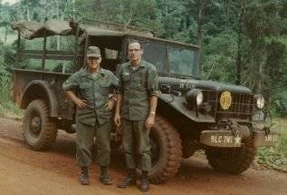 Two men stand near a Jeep, outside a dense jungle. Margins indicate the photo was taken October 1966.