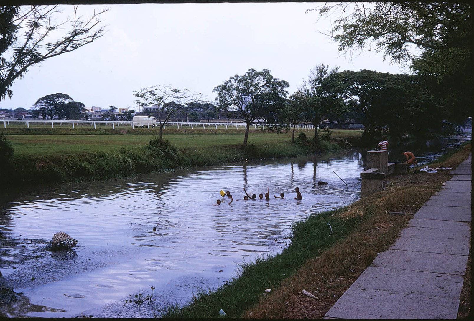 Asian children swimming in a canal.