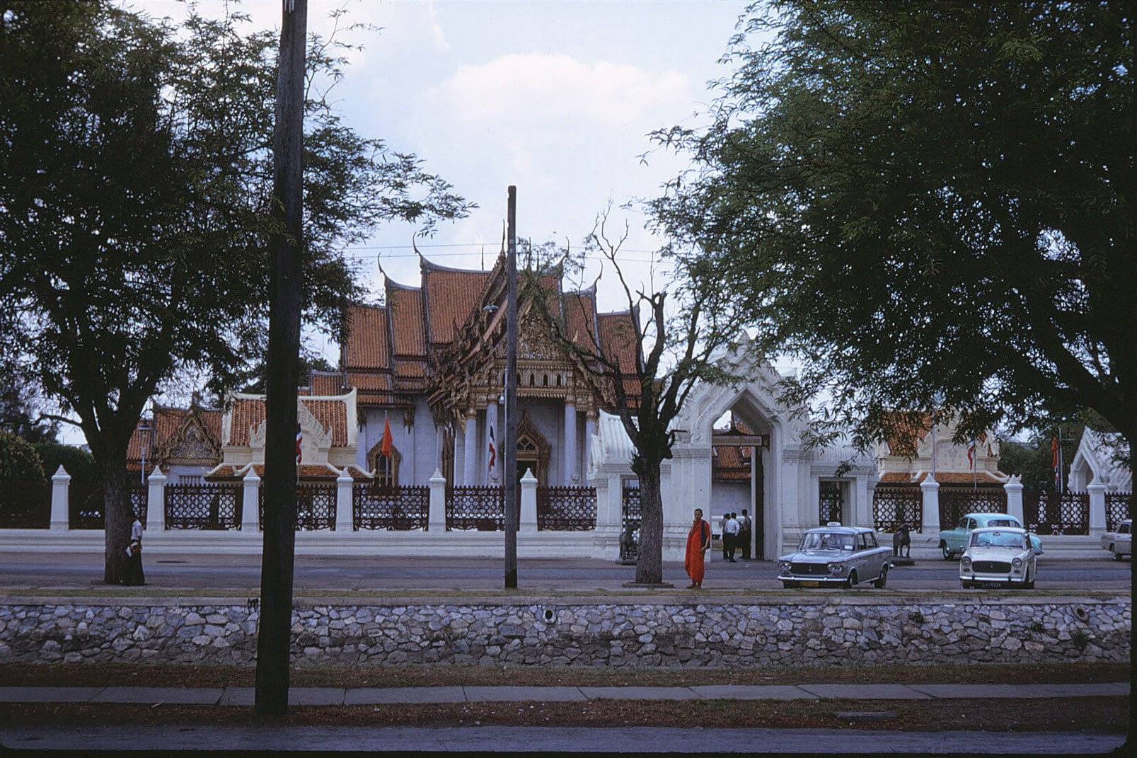 An ornate Asian temple with a monk in orange standing outside.