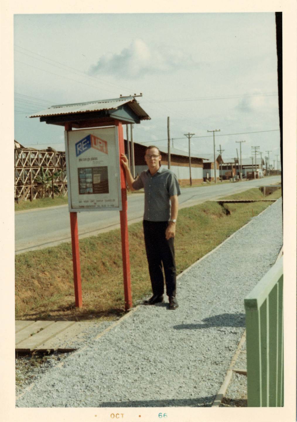 A young man in civilian clothes standing next to a sign that says "Re-Up!" Margins indicate photo is from October 1966.