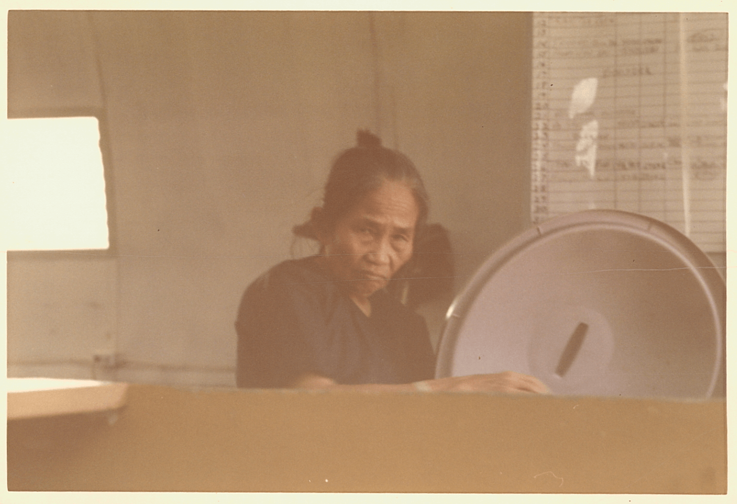 An Asian grandmother sitting at the side of a hospital bed.