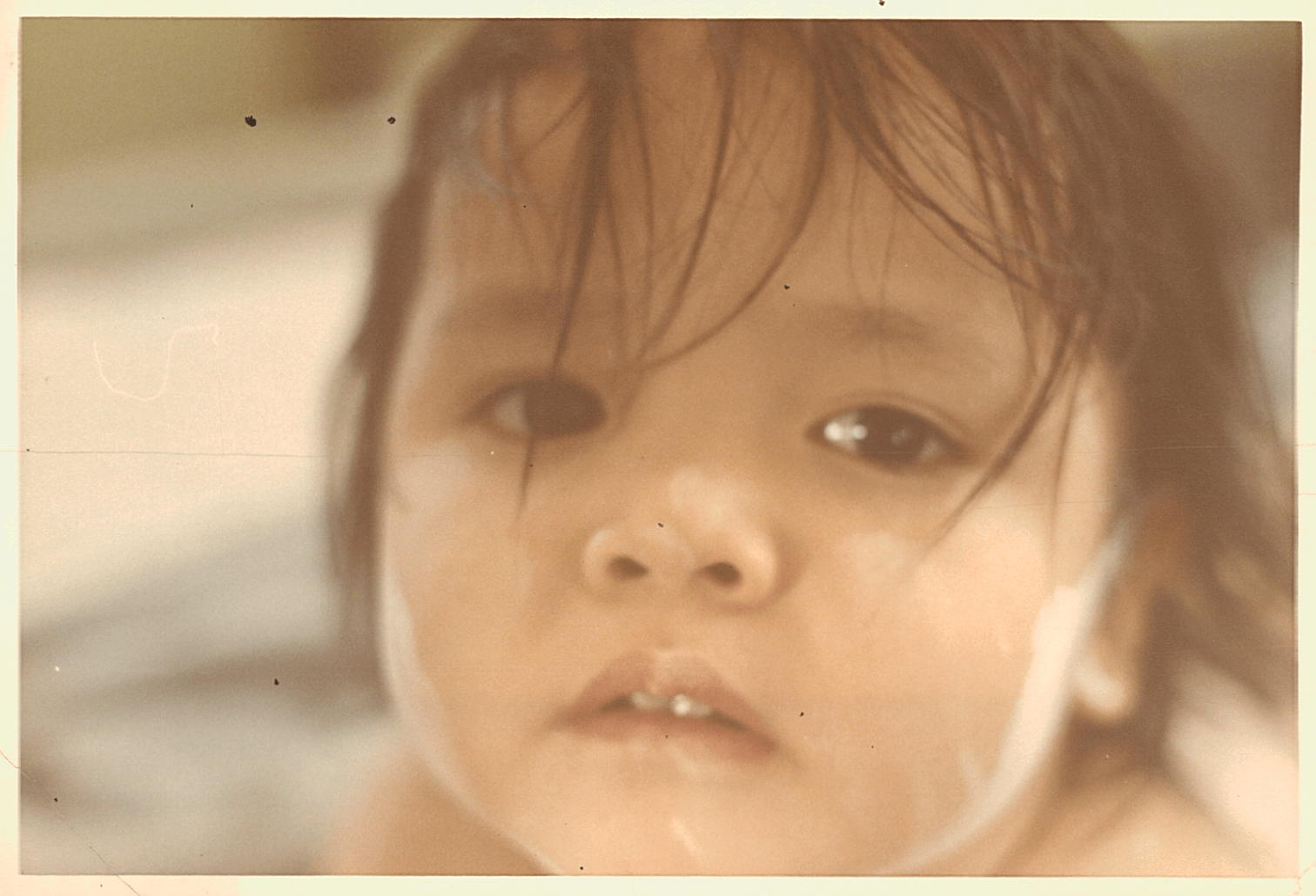 A close up of an Asian child, looking sad.