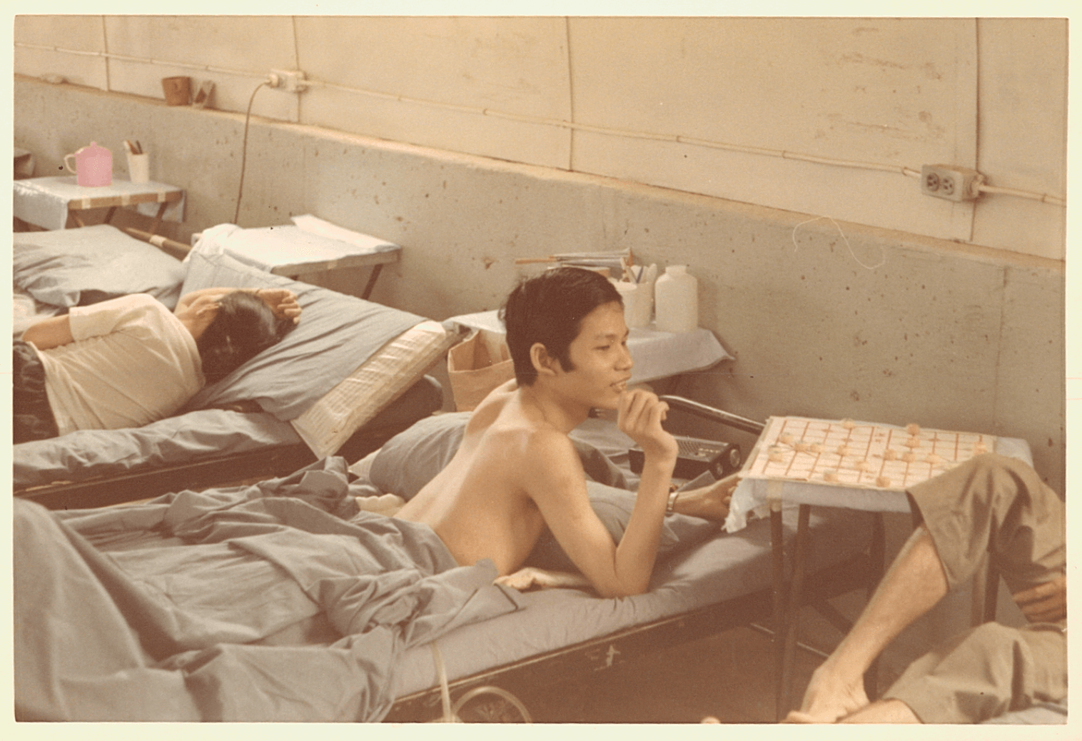 An Asian boy recuperates from his hospital bed, laying on his stomach.