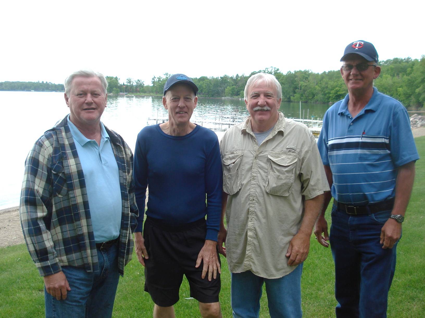 Contemporary photo of 4 older gentlemen standing by a lake.