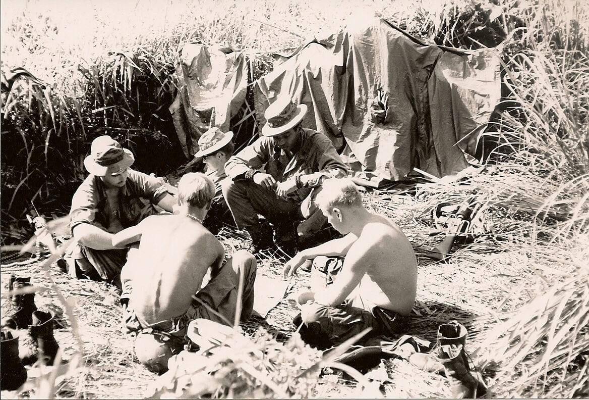 Soldiers relaxing in a clearing of grass.
