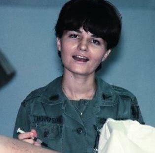 Young nurse holding syringe, patient in the foreground.