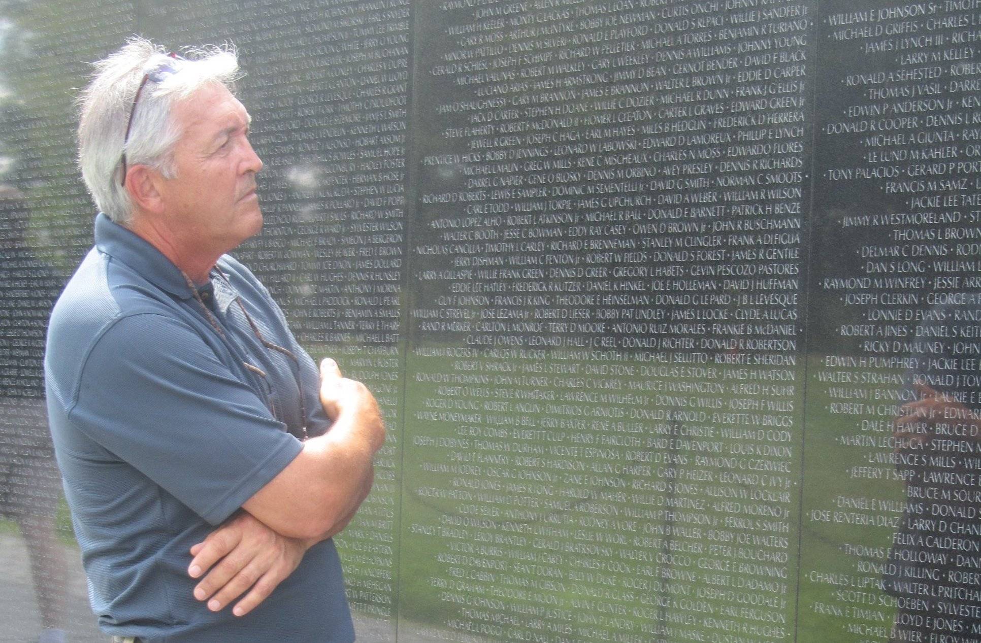 Older gentleman reading names on the Vietnam War Memorial.