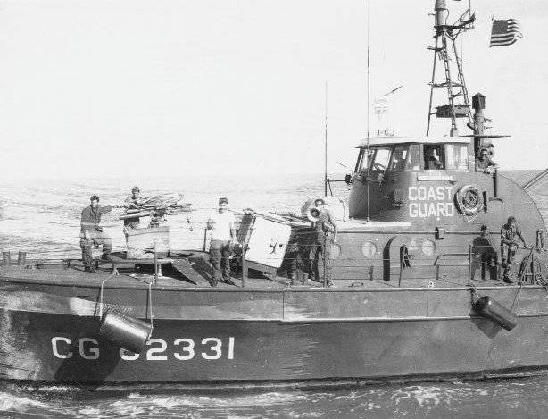 A Coast Guard boat with a small crew standing on deck.