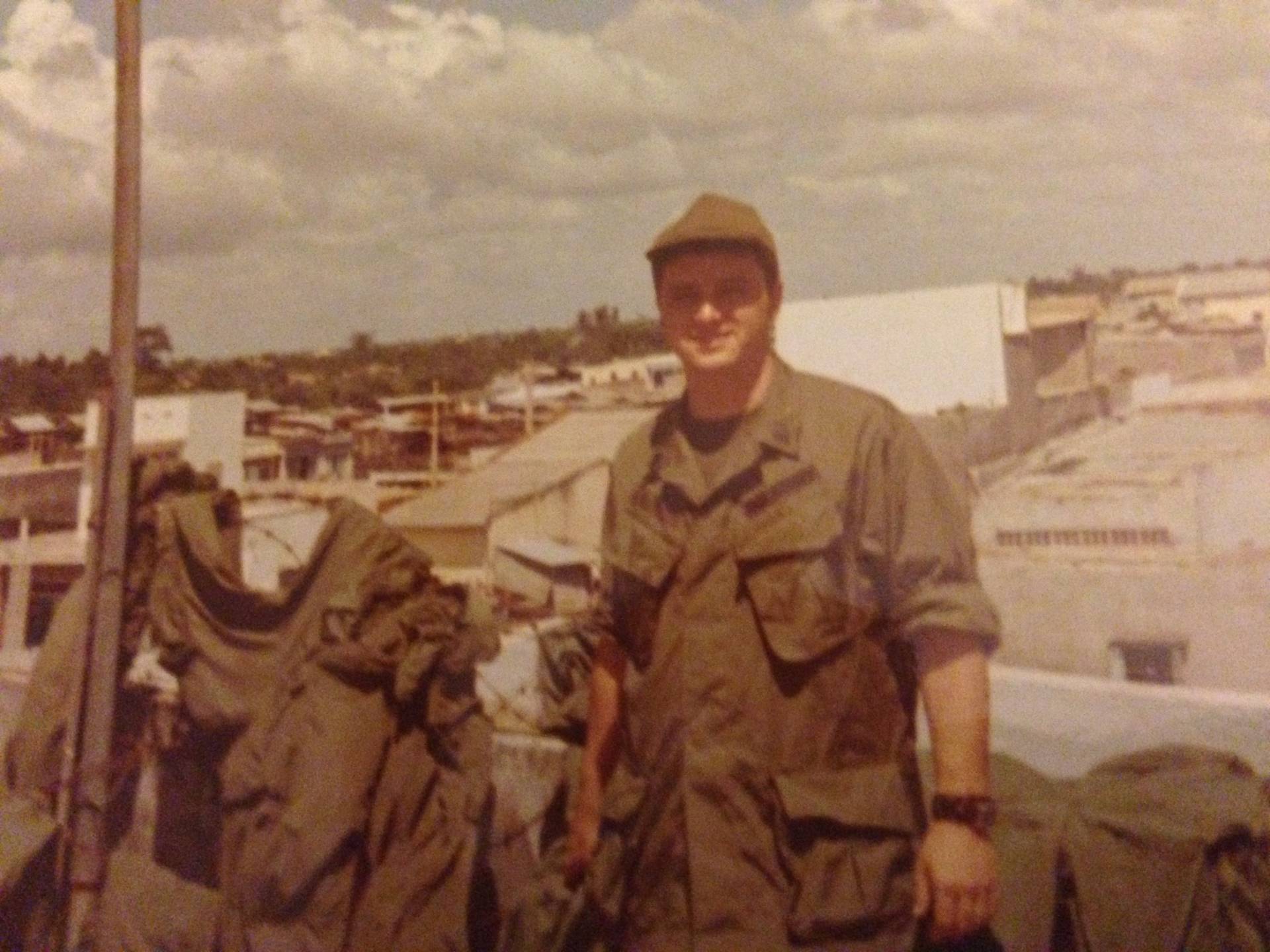 A young soldier on top of a structure, overlooking a village.