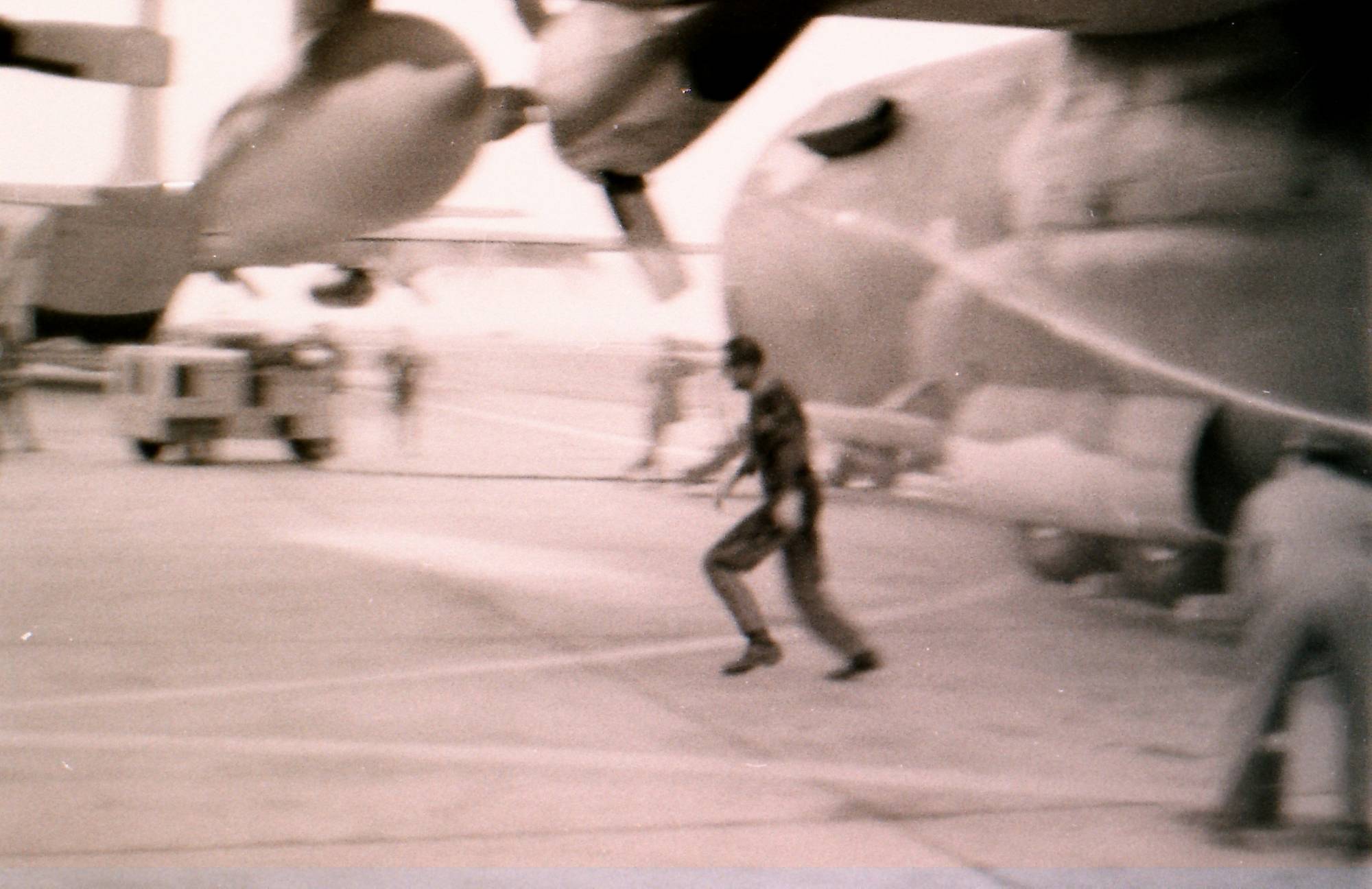 Blurry image of what looks to be a man running away from a plane on a tarmac.