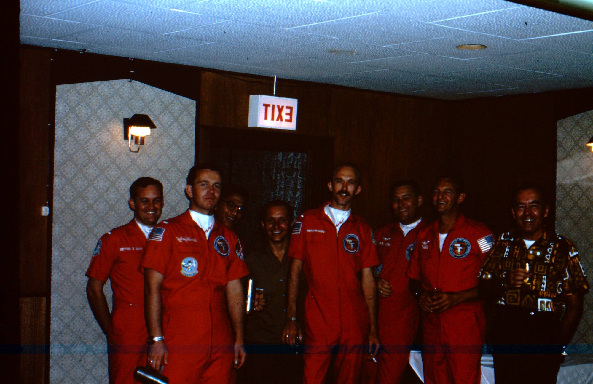 A bunch of men in orange flight jumpsuits in what appears to be a hotel.