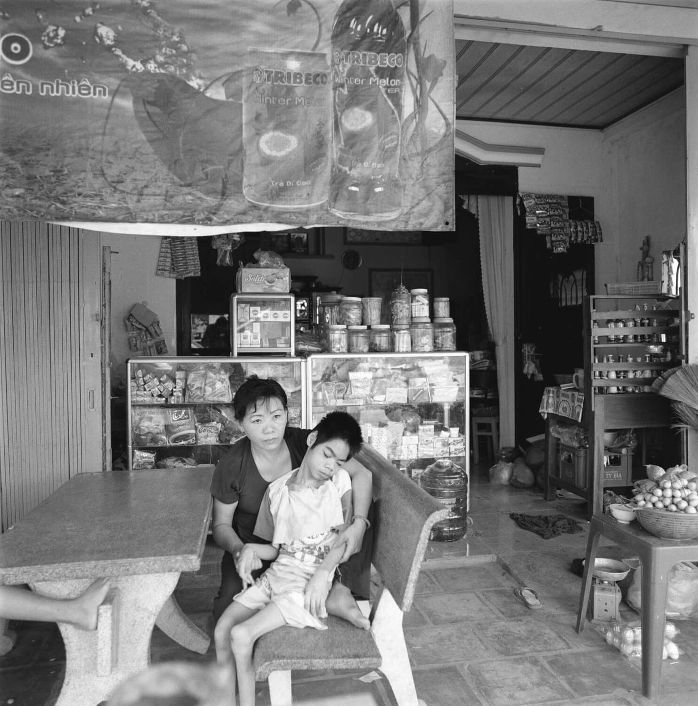 Asian mother and her deformed child, sitting in a booth at a shop or restaurant.