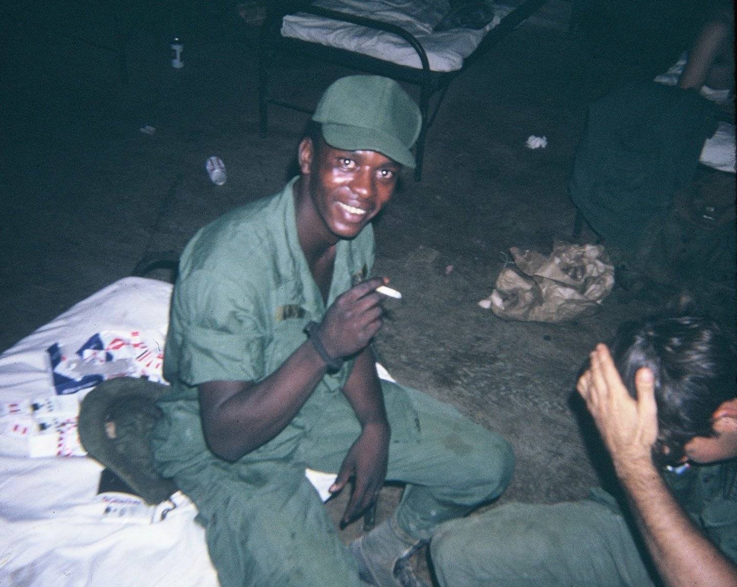 Young U.S. soldier sitting on his bunk at nighttime, smoking a cigarette.