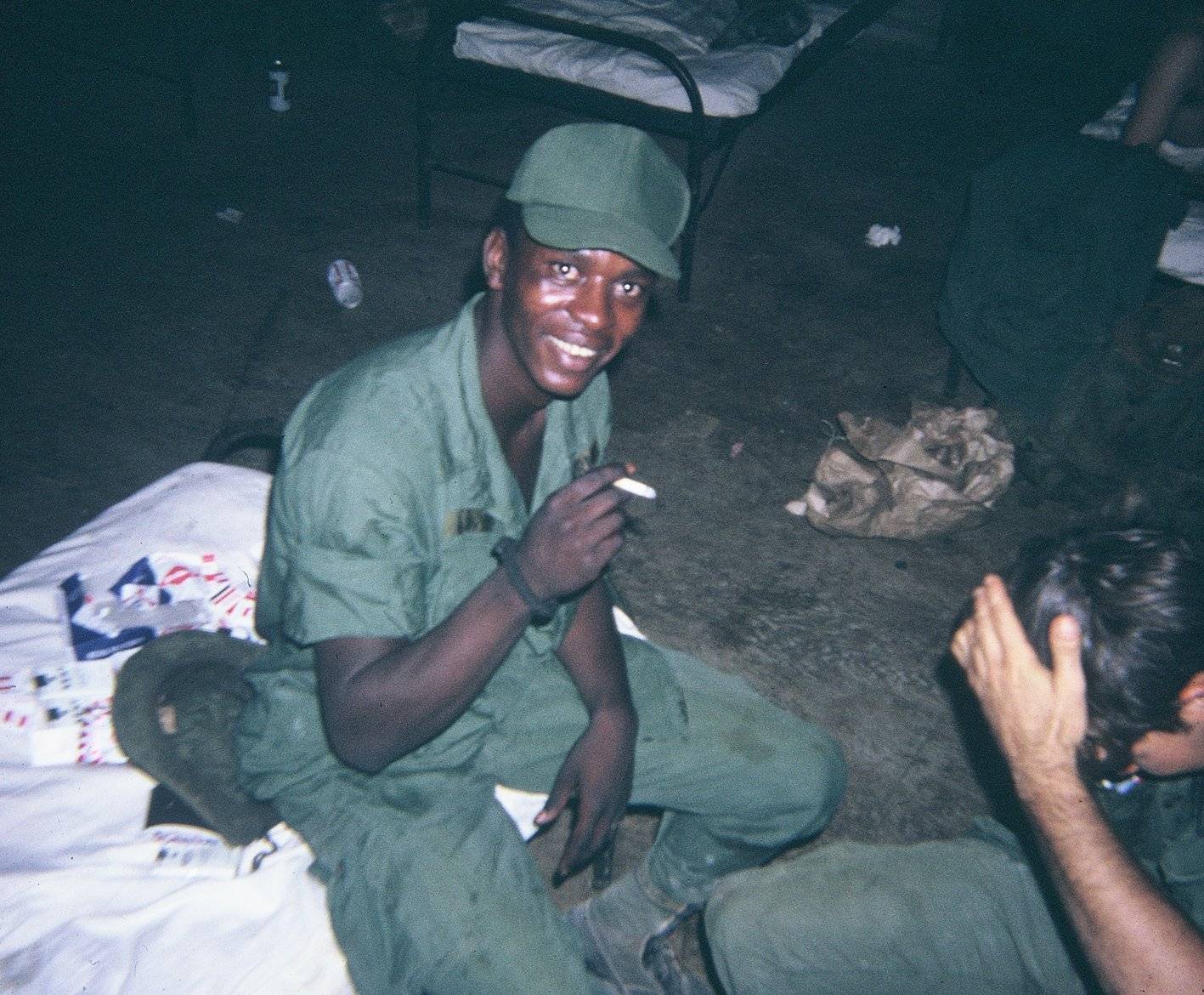 An African American soldier, smiling and smoking a cigarette.