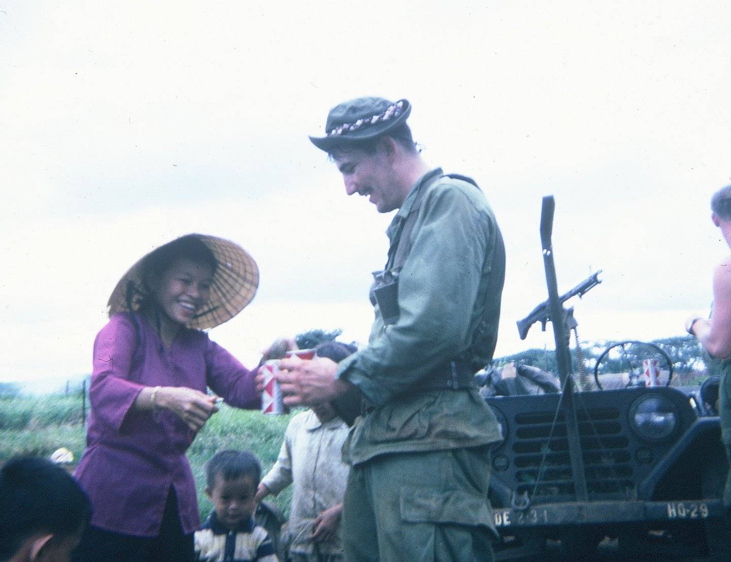 U.S. soldier handing out sodas to smiling Asian villagers.