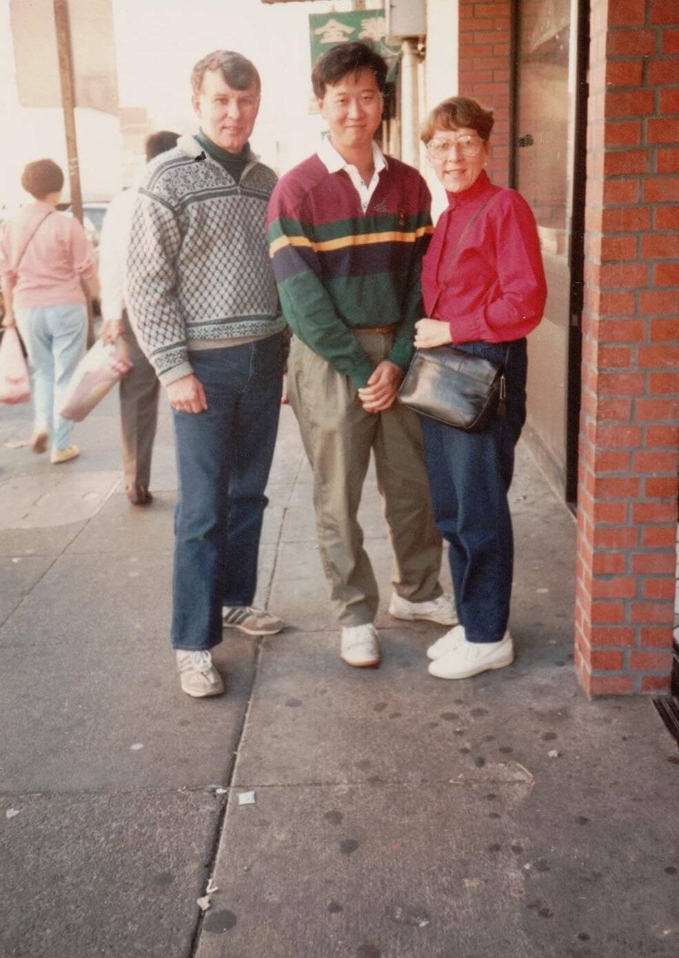 An American couple with a younger Asian man posed between them.