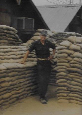 U.S. soldier standing among sandbags piled high.