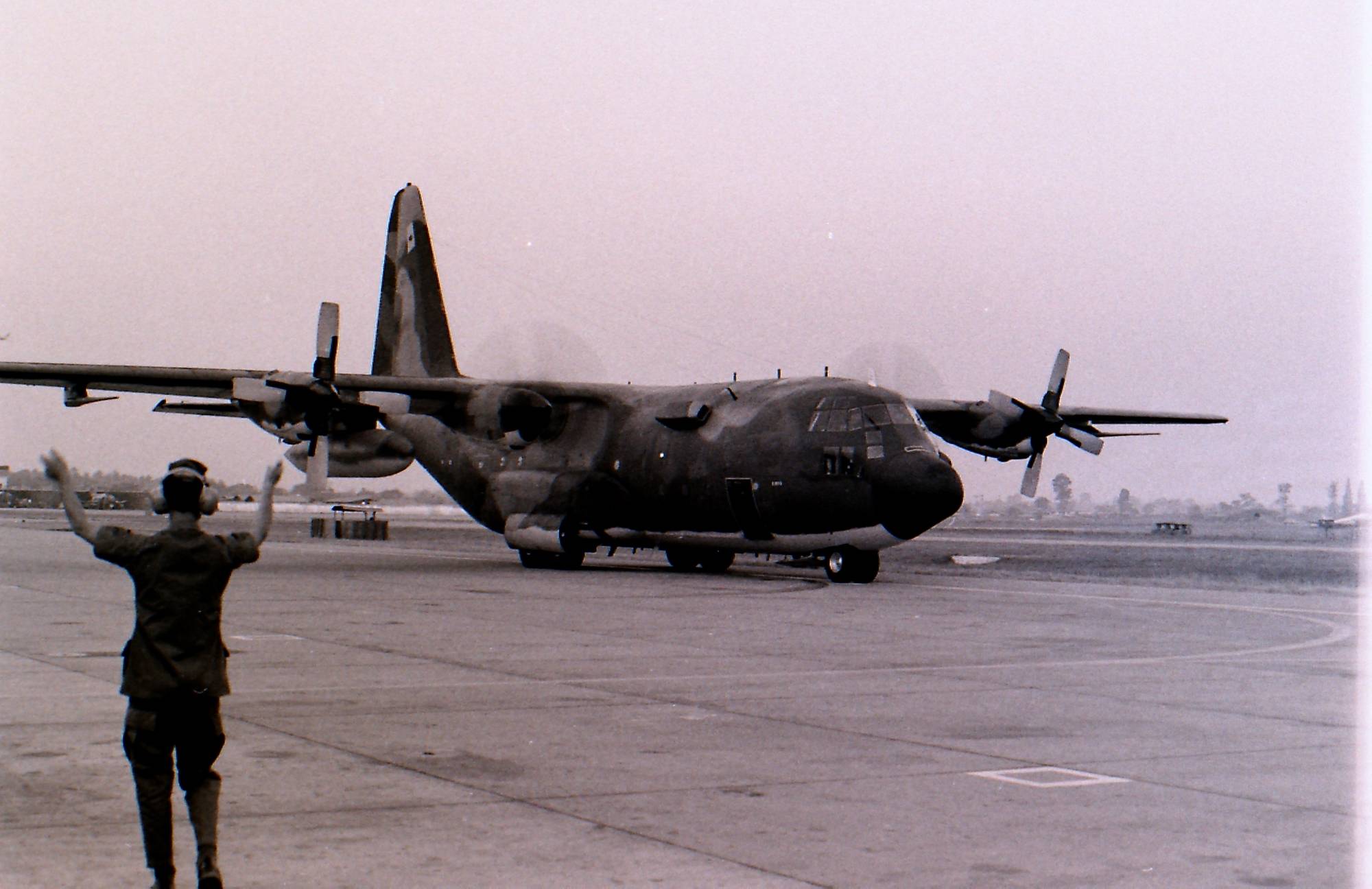A plane on a tarmac, a man directing traffic.