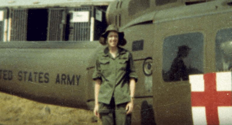 Young U.S. nurse in uniform standing next to a U.S. Army medical helicopter.