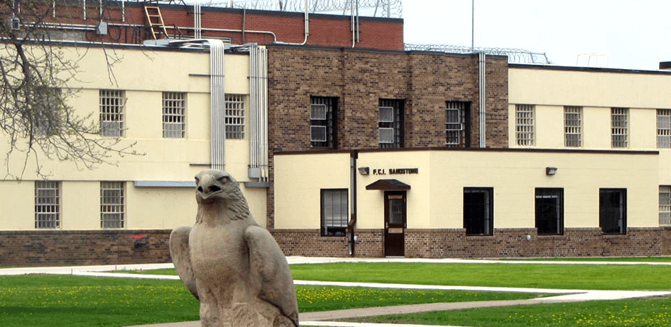 Exterior of Sandstone Federal Correctional Institution, bust of an eagle in the foreground.
