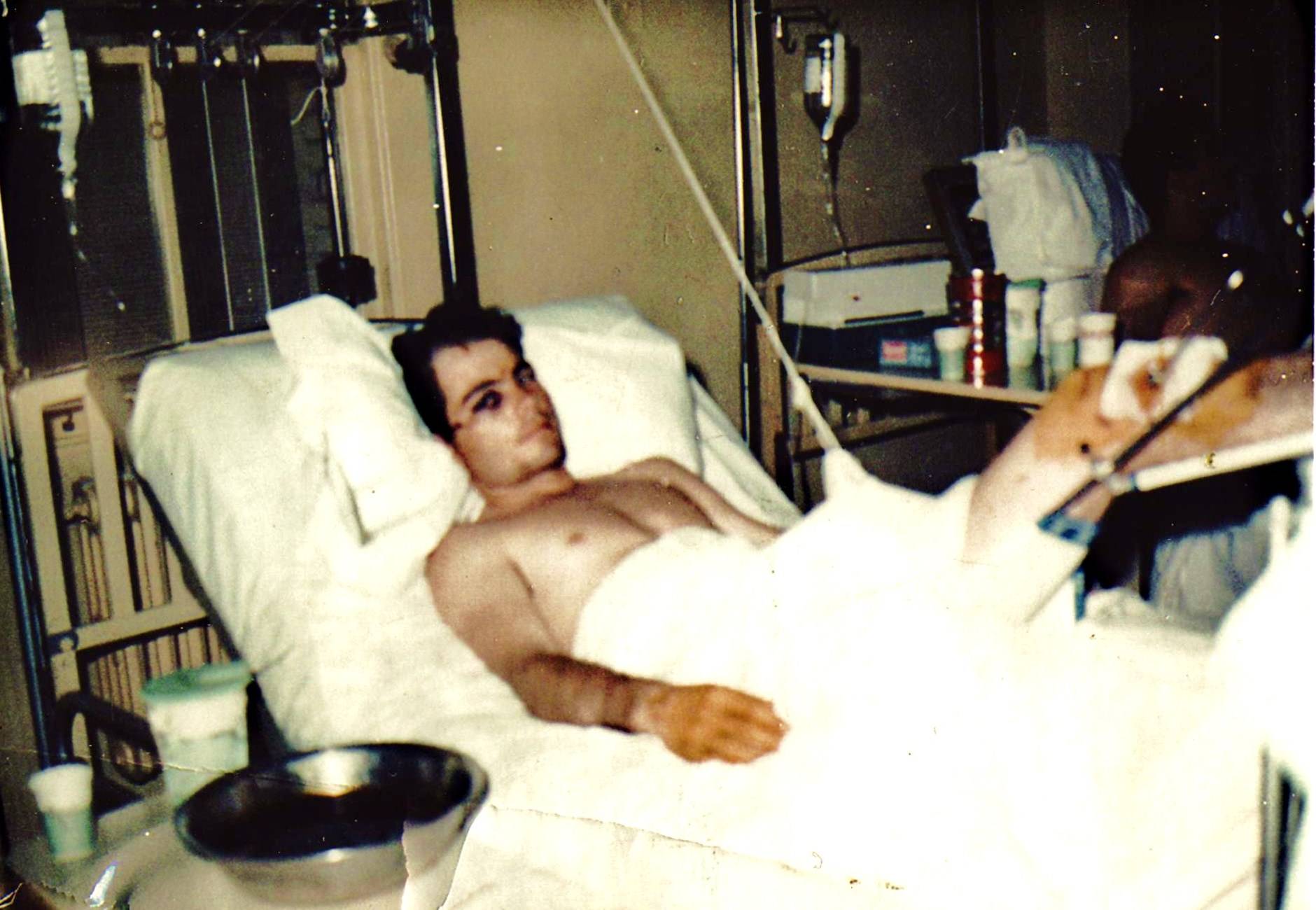 A badly bruised and wounded young man recuperating in a hospital bed.