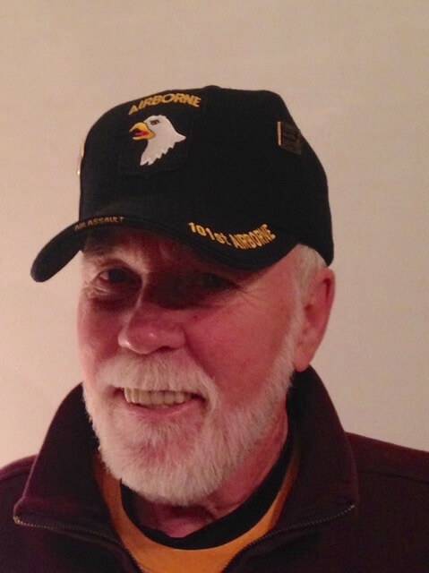 Contemporary photo of an aged and bearded Vietnam veteran, smiling and wearing a veteran's ball cap.