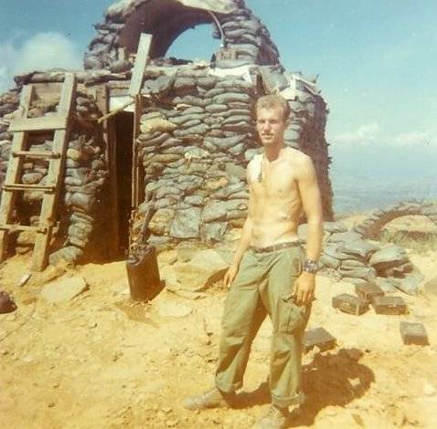 Young shirtless soldier standing outside a bunker.