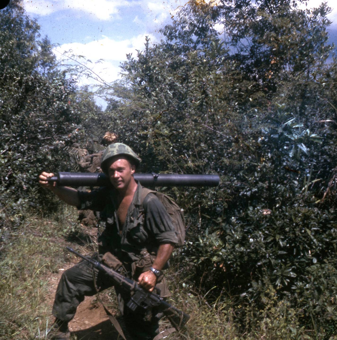 A U.S. soldier with a rifle in hand and a rocket launcher on his shoulder.