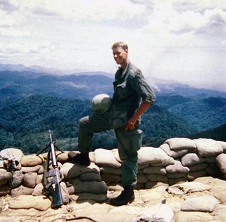 Young U.S. soldier on a high overlook of mountains and jungles.