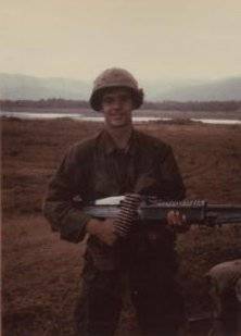 Young U.S. soldier out in a field, holding his rifle.