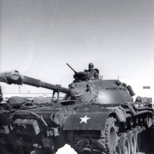 A tank with a soldier sitting on top of it.