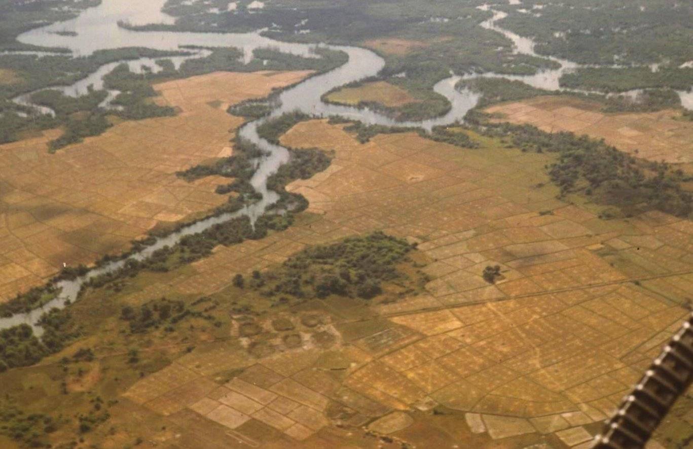 Overhead shot of a river and surrounding fields. Orange on the outsides, green around the river.