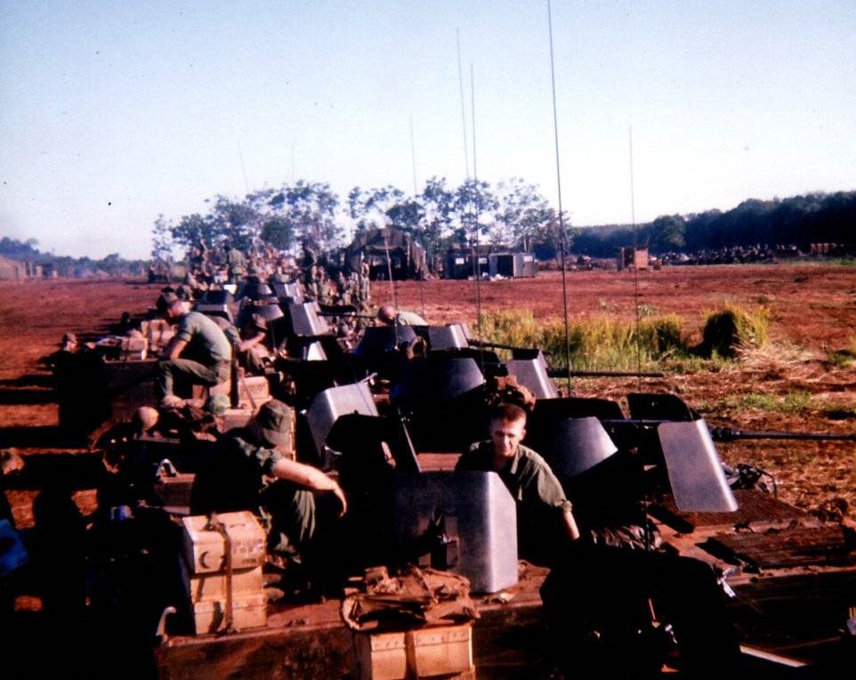 A group of soldiers at rest among some sort of armored gun units.
