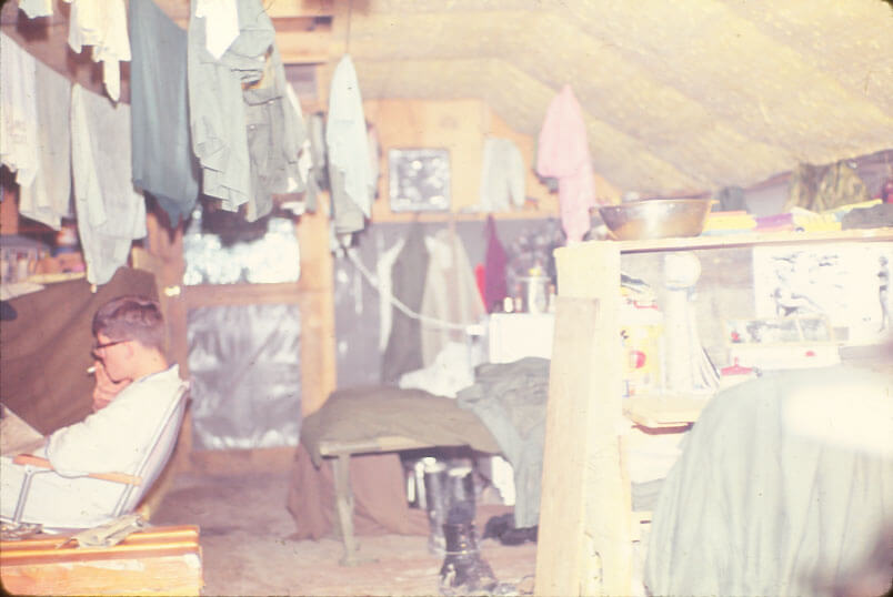 Interior of a cramped barracks with laundry hanging from the season.