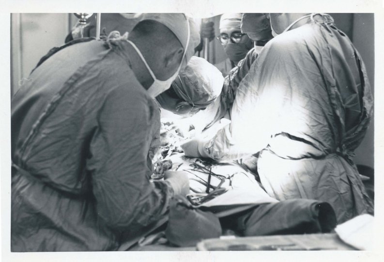 Close up of surgeons and operating team in scrubs, operating on a wounded soldier.