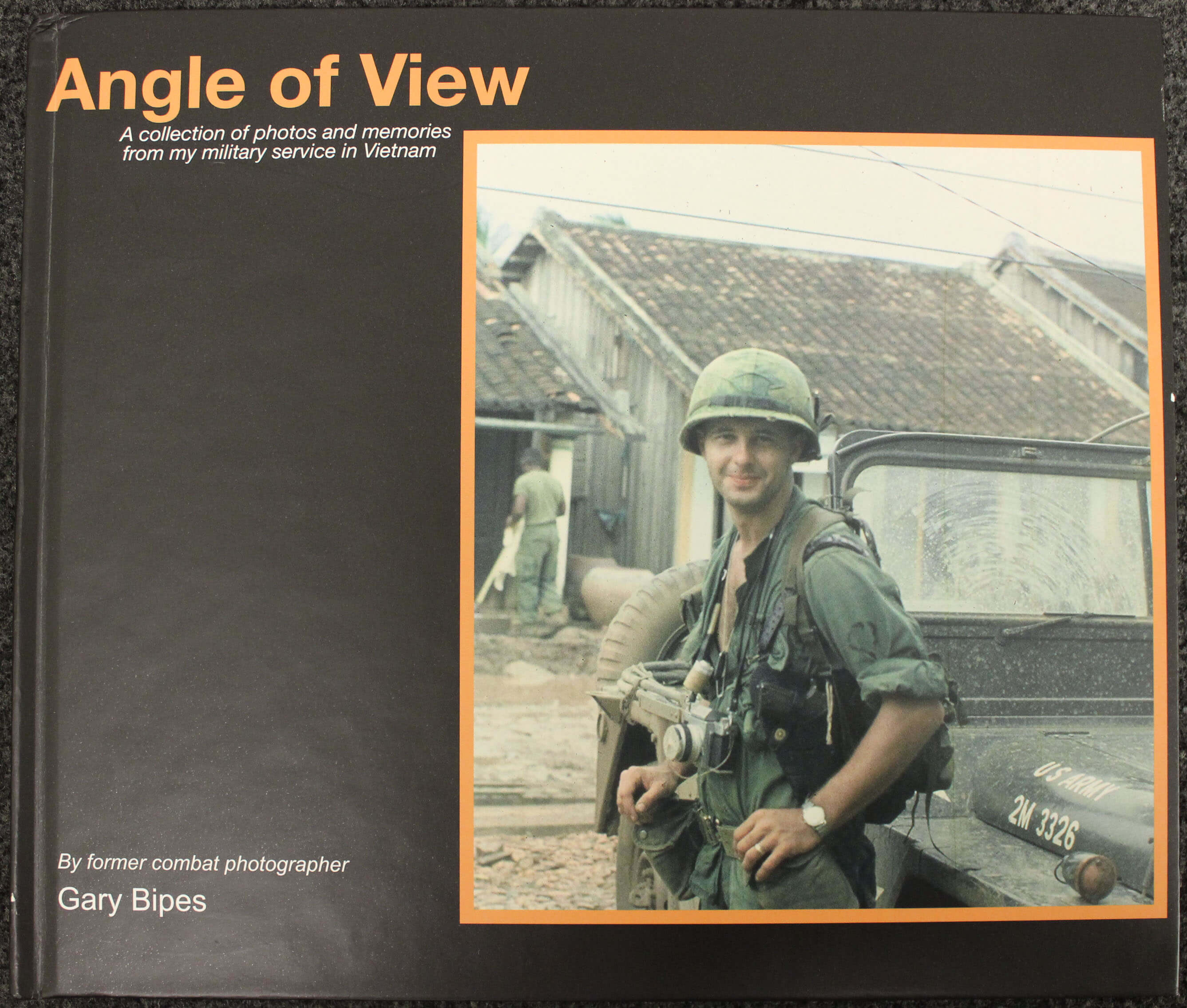 Cover of a book: "Angle of View: A Collection of Photos and Memories from my Military Service in Vietnam" - photo is of a young man in uniform and helmet with a camera around his neck.