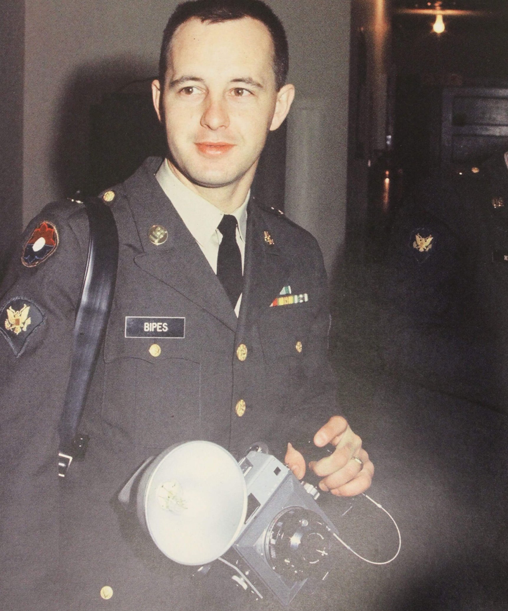 A young man in uniform with a camera in his hand.