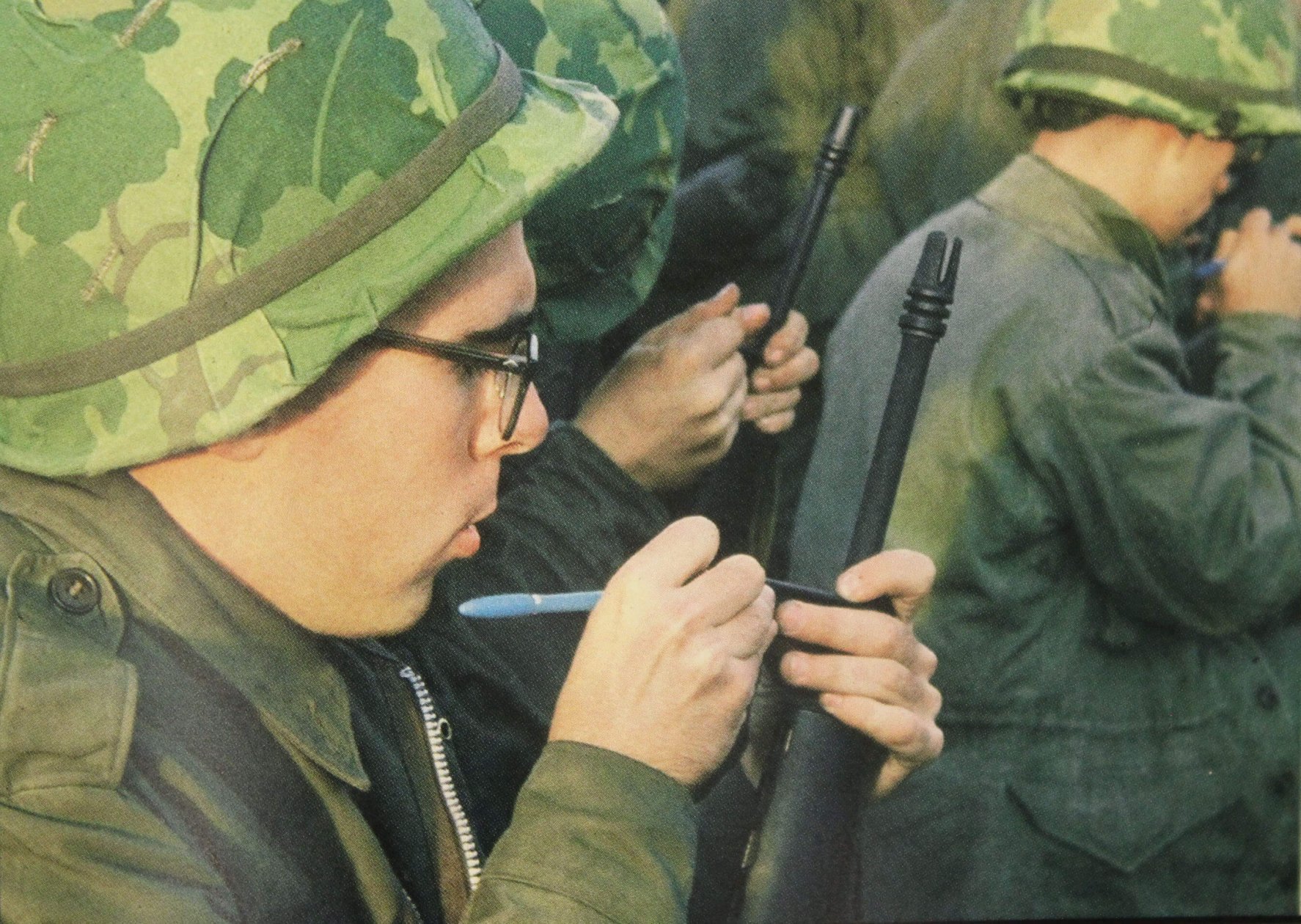 Young men inspecting their rifles, making marks on them.