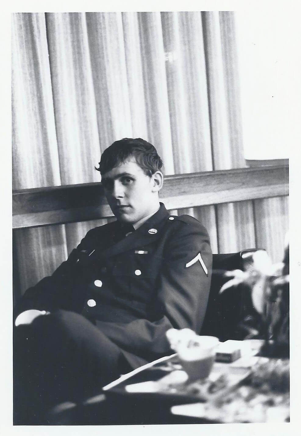 A young, sad-looking soldier looks into the camera.