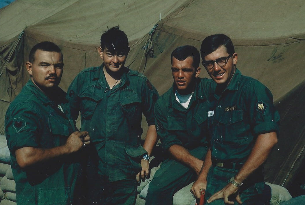 Four U.S. soldiers outside a canvas tent.